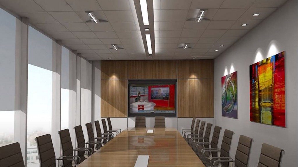 A long meeting table with a complete conference room AV system. Bright artwork hangs on the wall.