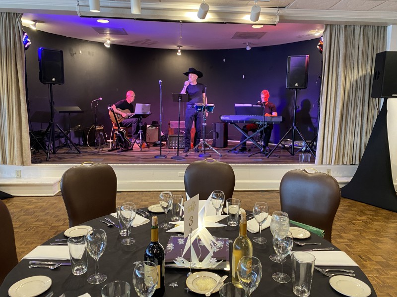 A singer, guitarist, and keyboard player do a sound check on stage as part of early event planning for a gala.