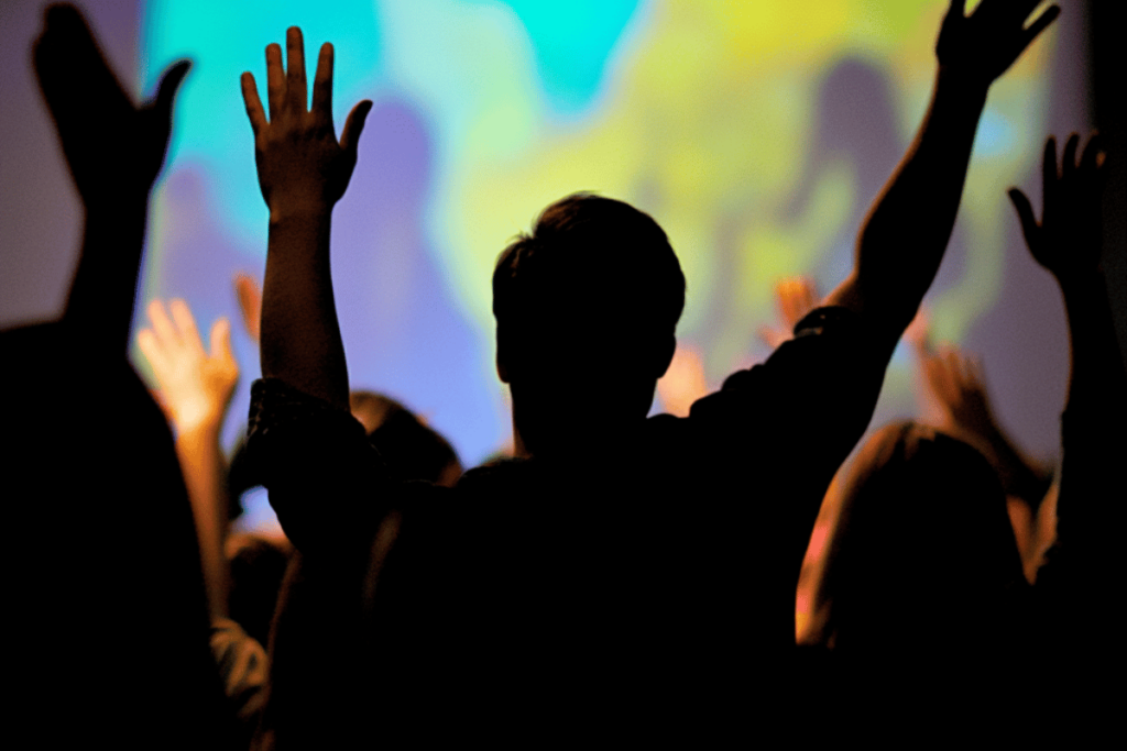 Youth ministry participants raise their hands in a vibrant worship setting, enhanced by dynamic lighting and sound systems designed for engaging experiences.